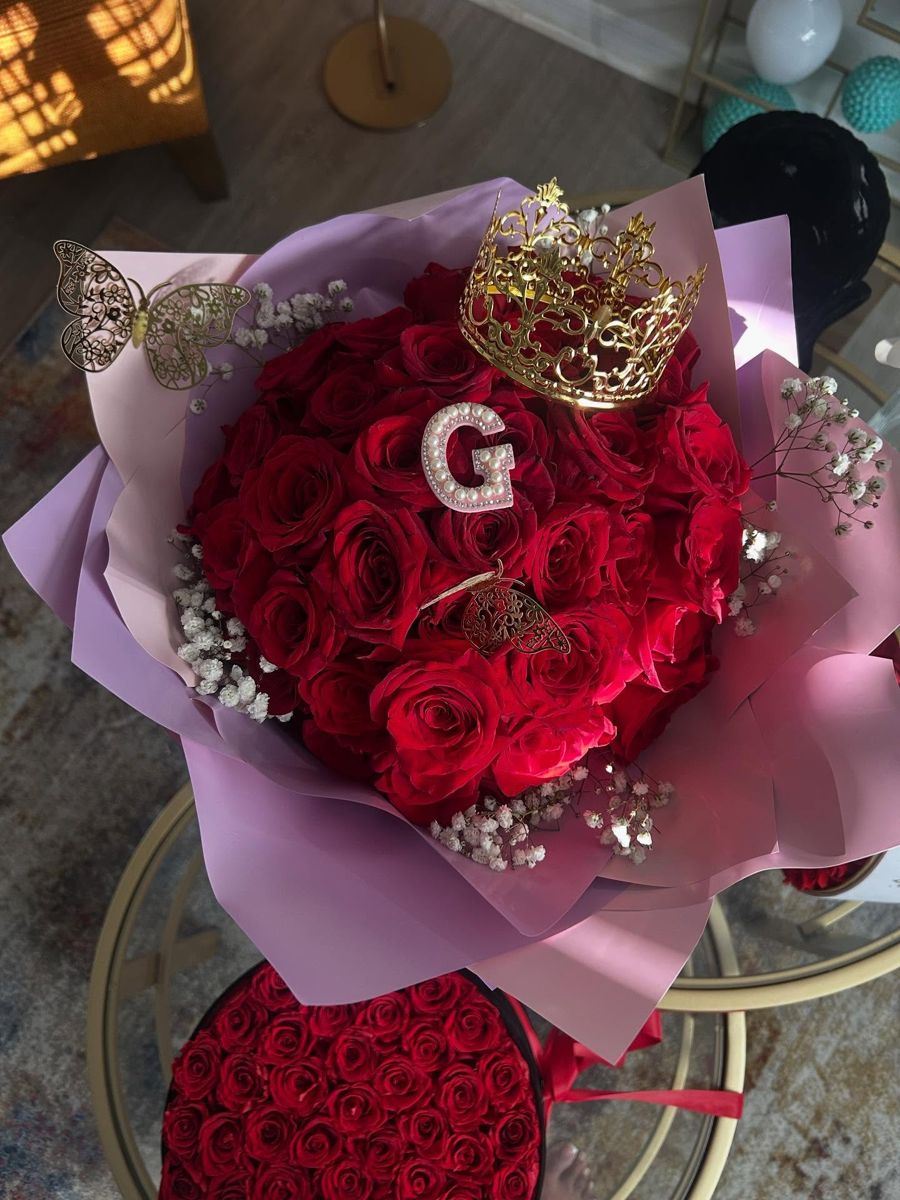 Red roses with a rhinestone letter G, gold crown and baby's breath in lilac wrap