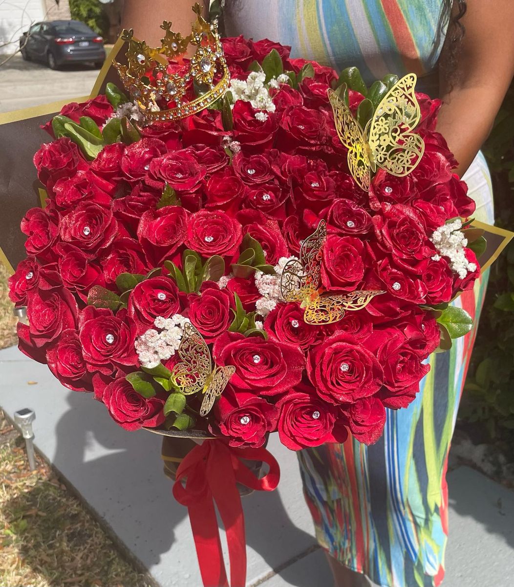 A large bouquet of red roses with a gold crown, butterflies and rhinestone centers