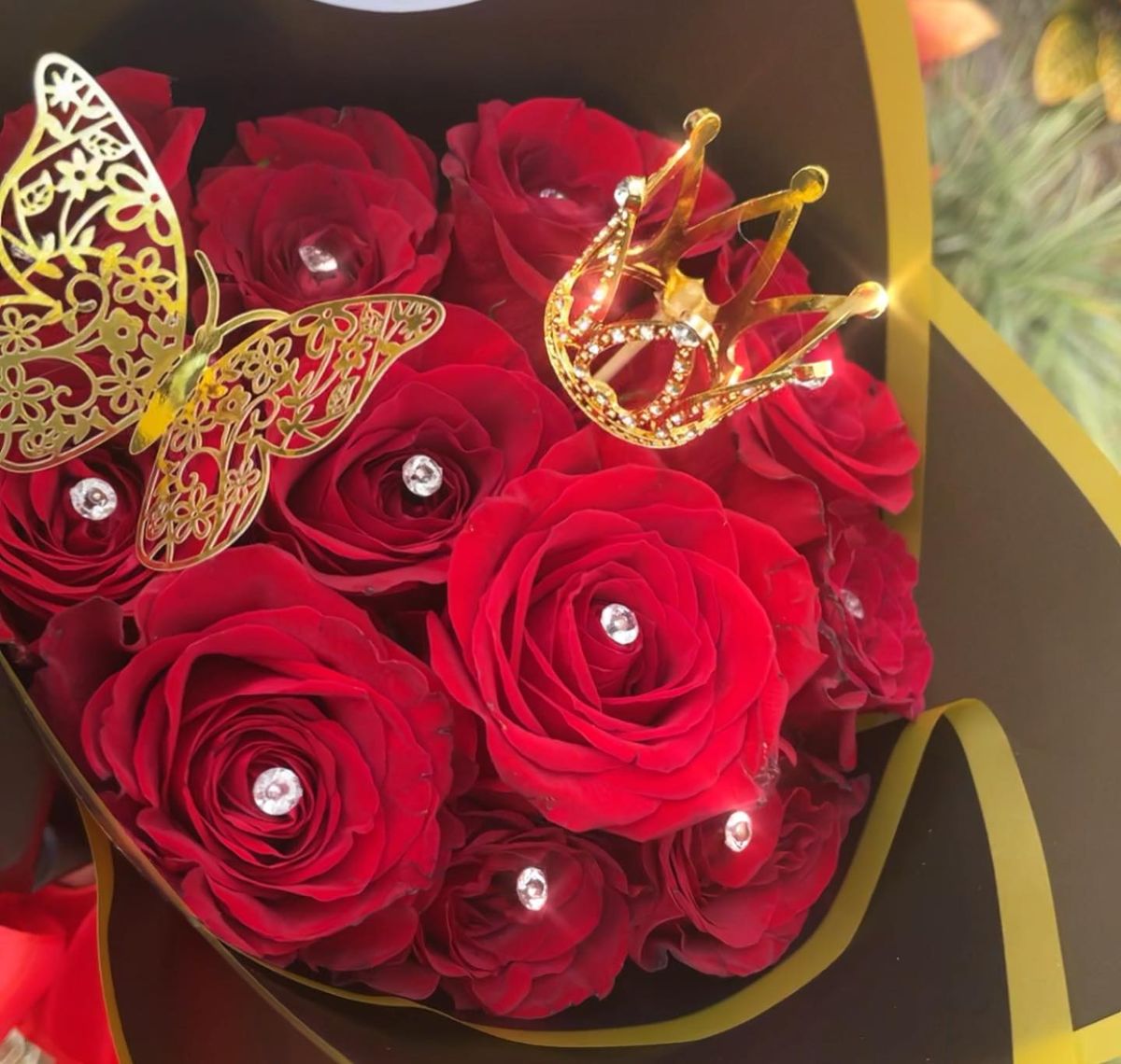 Red roses with rhinestone centers, a gold crown and filigree butterflies in black and gold wrap